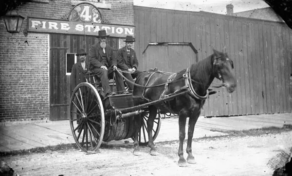 Citizen fire crew posing with horse-drawn fire wagon and hose reel outside No. 4 Fire Station